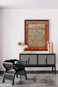 A black and white tribal-themed living room with intricate wooden furniture and an ornate framed artwork.