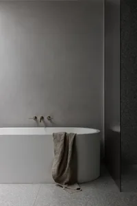 A minimalist bathroom with a freestanding concrete bathtub and a towel draped over the edge.
