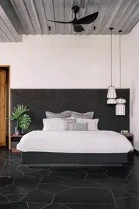 A modern bedroom with a concrete ceiling, glass fronted nightstands, and a floating bed.
