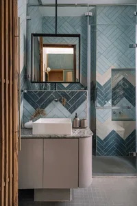 Modern bathroom interior featuring a blue tile pattern wall and a white sink on a grey countertop.