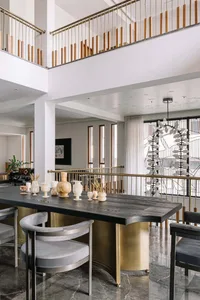 Modern dining room featuring a sleek black marble table with contemporary chairs, positioned against a modern staircase with 