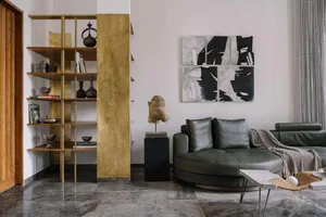 A modern living room with brass shelves, leather couch, marble floor, and abstract art on the wall.