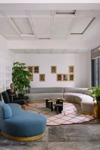 A modern living room featuring gray couches on a marble floor with framed artwork on the wall.