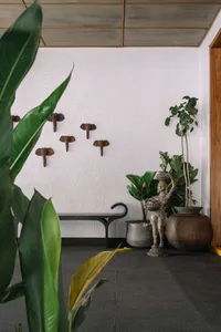 A modern lobby featuring concrete, metal, and wood materials with potted plants and elephant decorations on the wall.