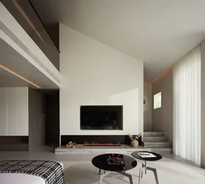 Modern minimalist living room featuring concrete walls, a flat-screen television, and a fireplace.
