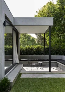 Modern minimalist patio area with concrete seating and black metal frame furniture
