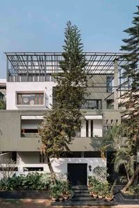A modern residential pavilion constructed with concrete and featuring large windows and a pergola.