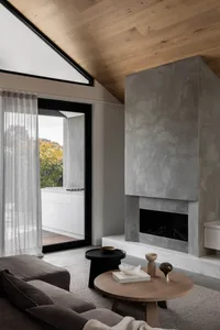 A modern living room with concrete walls, wooden floor, and a cozy sofa with throw pillows.