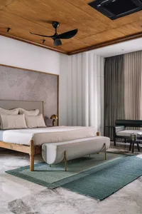 Modern minimalist bedroom featuring a wooden floor, upholstered furniture, and a large window with curtains.