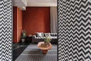 A stylish modern living room with textured wallpaper, a dark wood coffee table, and a comfortable grey sofa.