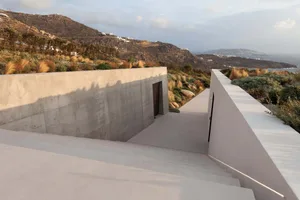 A modern residential building with a concrete staircase leading to the entrance.