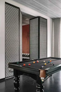 An industrial-style pool room with a black concrete floor, a pool table with billiard balls, and decorative floor-to-ceiling 