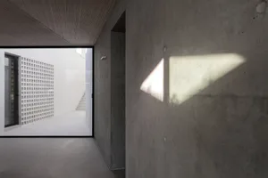 Modern building interior with concrete walls and a triangle-shaped light shadow.