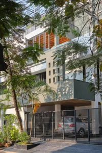 Modern residential building entrance featuring a concrete facade and metal gate.