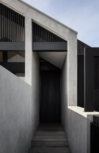 Contemporary concrete entryway with wooden flooring and black metal railings.