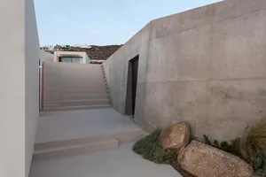A modern minimalist entryway with a concrete staircase and wall.