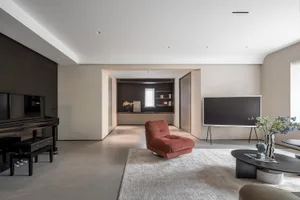 A modern living room with concrete flooring, minimalist decor, and a single red plush chair.