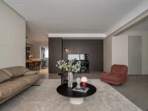 A modern living room with a mix of materials including leather, wood, and glass.