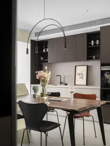 A modern residential kitchen with wooden cabinets, a dining table, and a vase of flowers.