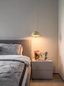 A minimalist bedroom featuring soft, comfortable furniture and warm lighting.
