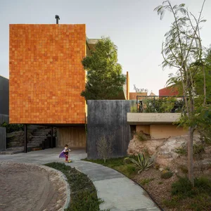 A modern residential building with exterior walls of concrete and orange tiles.