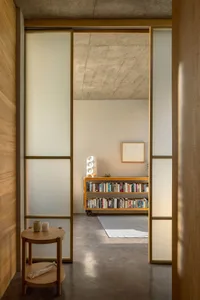 A minimalist interior with concrete walls, wooden furniture, and a glass window.