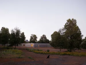 Modern structure with concrete exterior in a natural setting with trees and flowers.