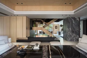 A modern living room featuring a marble floor and black glass coffee table.