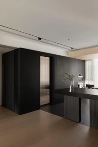 現代簡約住宅室內，廚房擁有黑色混凝土牆面與地板，以及黑色木質櫥櫃。
