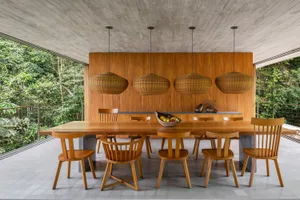 Modern residential dining room featuring wooden furniture and ceiling lights.