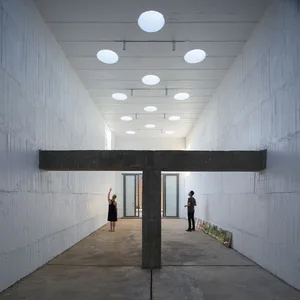 A minimalist exhibition space with concrete walls and a concrete beam