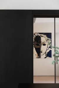 Modern minimalist interior featuring a mixed media artwork depicting a stylized, abstract portrait.