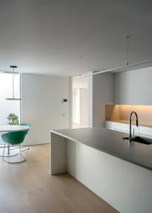 Modern minimalist kitchen featuring concrete countertops and wood flooring.