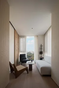 Modern minimalist living room featuring neutral-toned furniture and a view of the city.