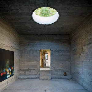 Concrete walls and ceiling with a circular window in a minimalist interior design setting.