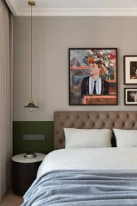 Modern bedroom featuring a beige upholstered bed with patterned bedding, fabric wall border, and hanging light fixture.
