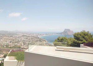 Modern residential home with concrete exterior overlooking a coastal cityscape and ocean.