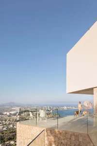 A minimalist architectural design featuring a residential exterior with glass, stone, and concrete materials.
