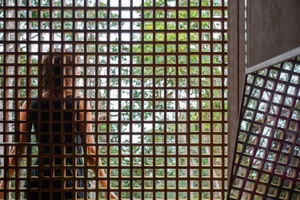 Modern interior design featuring a wooden grid panel with a grid of small, square openings allowing light to filter through.