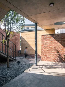 Modern patio featuring brick walls and concrete patio area with a tree.