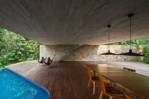 Modern living room with a large pool, concrete walls, and wooden floors.