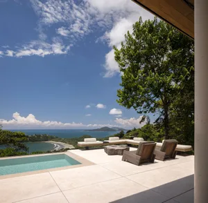 Contemporary outdoor residential deck featuring a pool, lounge chairs, and panoramic ocean views.