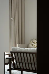 A minimalist living room with light-colored textiles and a soft, textured sofa, featuring a tall, slim floor lamp and a delic