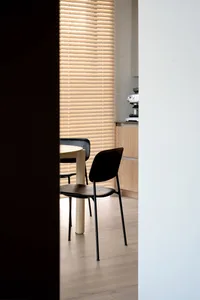 Minimalist kitchen with black chairs and wooden table, blinds closed.