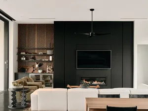 Modern living room with black walls and metal paneling, featuring a white sectional sofa, wooden coffee table, and black ceil