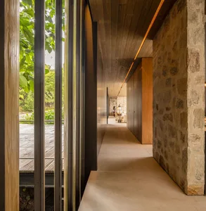 A modern corridor featuring exposed wooden beams, concrete floor, and glass walls.