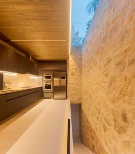 A modern kitchen with stone walls, wooden ceiling, and stainless steel appliances.
