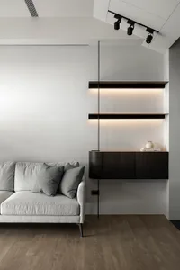 Modern living room with a white sofa, black shelves, and wooden flooring.