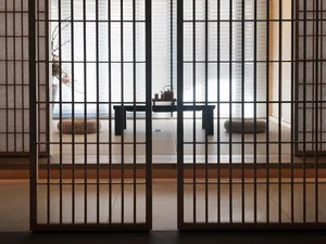 Modern living room with a dark wood floor, minimalist furniture, and large windows.