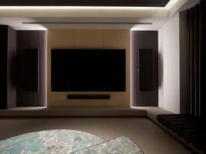 A modern media room featuring a large flat-screen TV, surround sound speakers, and wooden accents.
